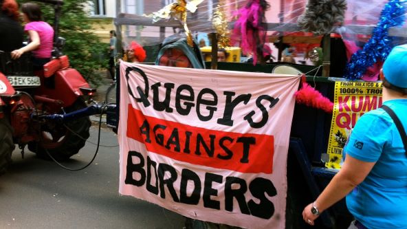 People holding sign that says "Queers against borders"